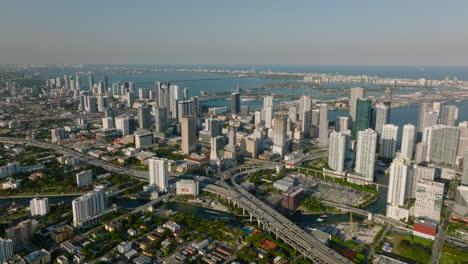Aerial-panoramic-shot-of-modern-urban-borough,-high-rise-buildings-along-coast-and-busy-transport-infrastructure-at-golden-hour.-Miami,-USA