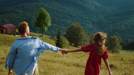 una hermosa pareja explora la naturaleza en la colina. una familia emocionada se da la mano en las montañas.