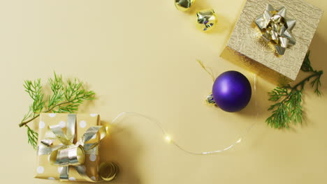 video of gold and purple christmas decorations and presents on yellow background