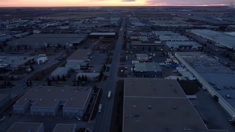 Long-haul-truck-leaving-warehouse-area,-heading-towards-the-sunrise