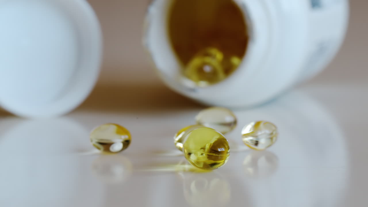Fish oil omega 3 supplements spilling out of a packer bottle on a white background