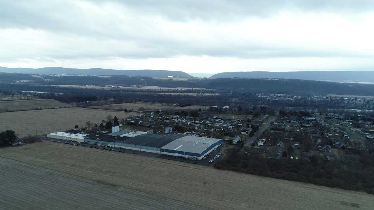 A drone shot moving forward through a city, passing over commercial buildings and nearby homes in a mixed urban neighborhood