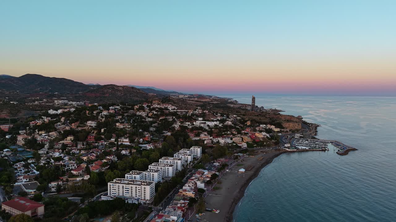 Beautiful sunset aerial rise up view over Playa El dedo Beach, Malaga Spain