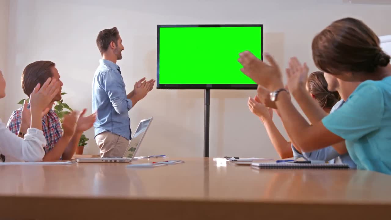 Creative team looking at television with green screen