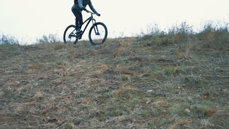 athlete cyclist man with backpack and helmet riding a mountain bike down the hill