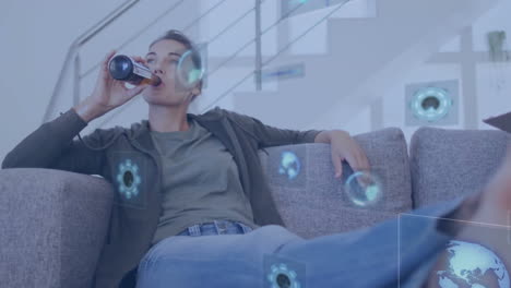 animation of data processing over caucasian woman sitting on sofa drinkking beer