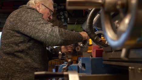 hombre maduro ingeniero mecánico trabajando en una máquina de torno en el taller