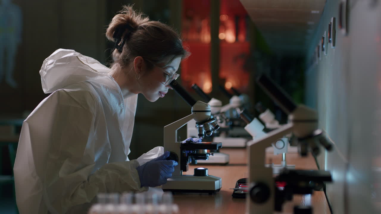microbiólogo femenino analizando muestras con microscopio en laboratorio