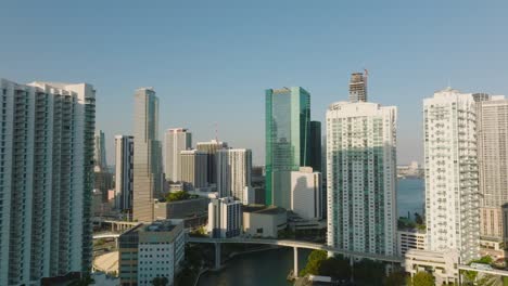 backwards reveal of high rise modern apartment buildings in residential urban borough. skyscrapers along river lit by bright afternoon sun. miami, usa