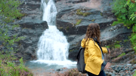 mujer feliz caminando cerca de una cascada