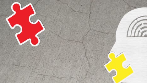 animation of green, yellow and red puzzle pieces falling over model of human head on grey background