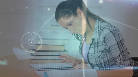 Animation-of-network-of-connections-over-biracial-woman-sitting-and-reading-at-desk