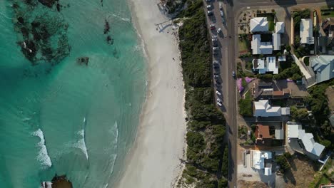 top down split aerial view above the middle of the beach and the residential area with moving cars, drone