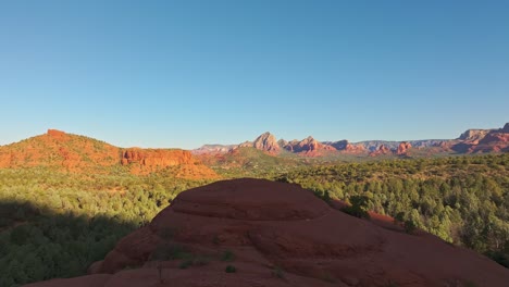 Drone-dolly-flies-out-to-view-of-Submarine-Rock,-Sedona-Arizona-at-midday,-epic-wide-angle-view