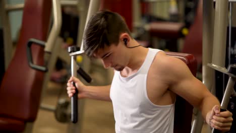 extreme closeup of teen bodybuilder doing vertical deltoid fly exercises on a machine at a fitness gym