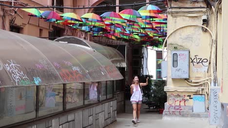 girl vlogging in colored umbrellas street with graffiti