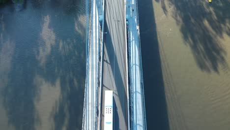 Slow-drone-panning-up-shot-of-the-University-of-Queensland-UQ-campus,-Flying-over-UQ's-Green-Bridge,-drone-passes-through-bridge-structure