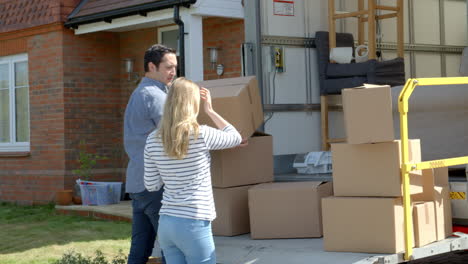 couple unpacking moving in boxes from removal truck