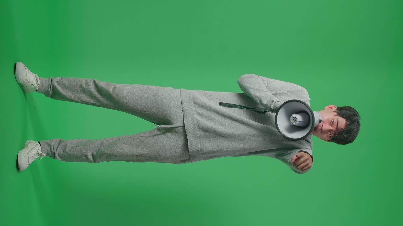 Full Body Of Asian Man Speaking On Megaphone In The Green Screen Studio