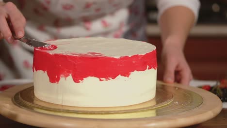 woman decorating a beautiful white cake with red icing