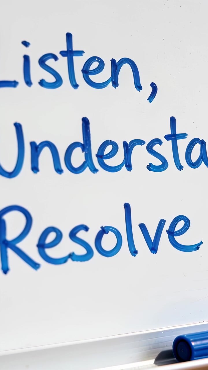 Vertical video: Camera centering whiteboard Listen, Understand, Resolve in boardroom with marker