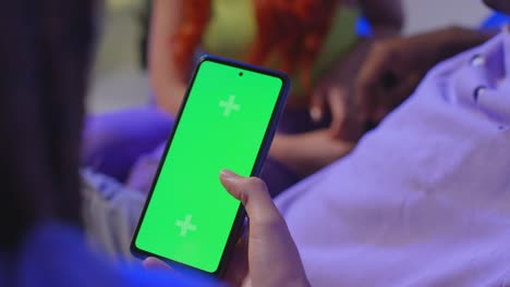 close up of woman with green screen mobile phone sitting with gen z friends talking and sharing posts 8