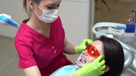 female dentist taking off protective glasses and mouth expander after finishing the procedure of teeth withening. shot in 4k.