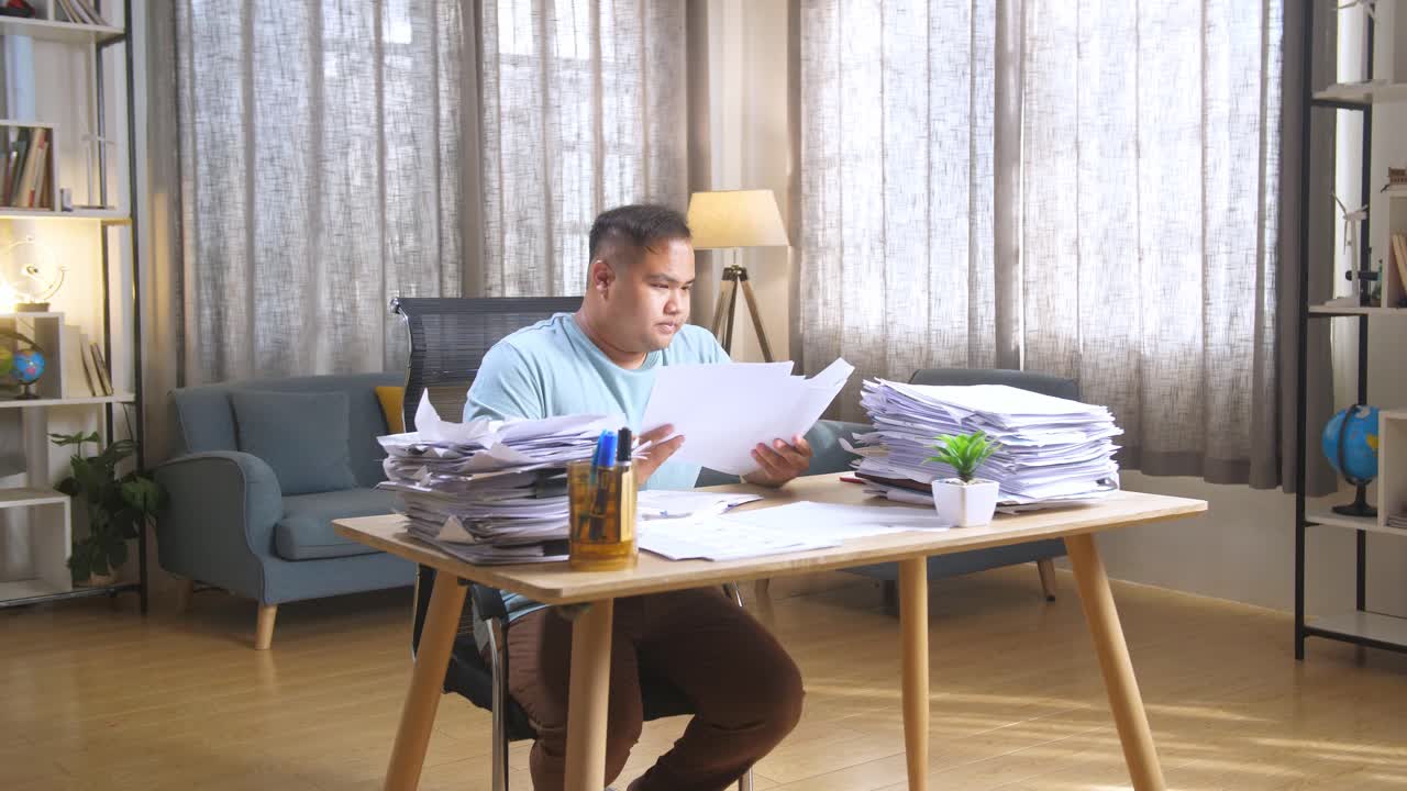 Stressed Man with a Stack of Papers at Home