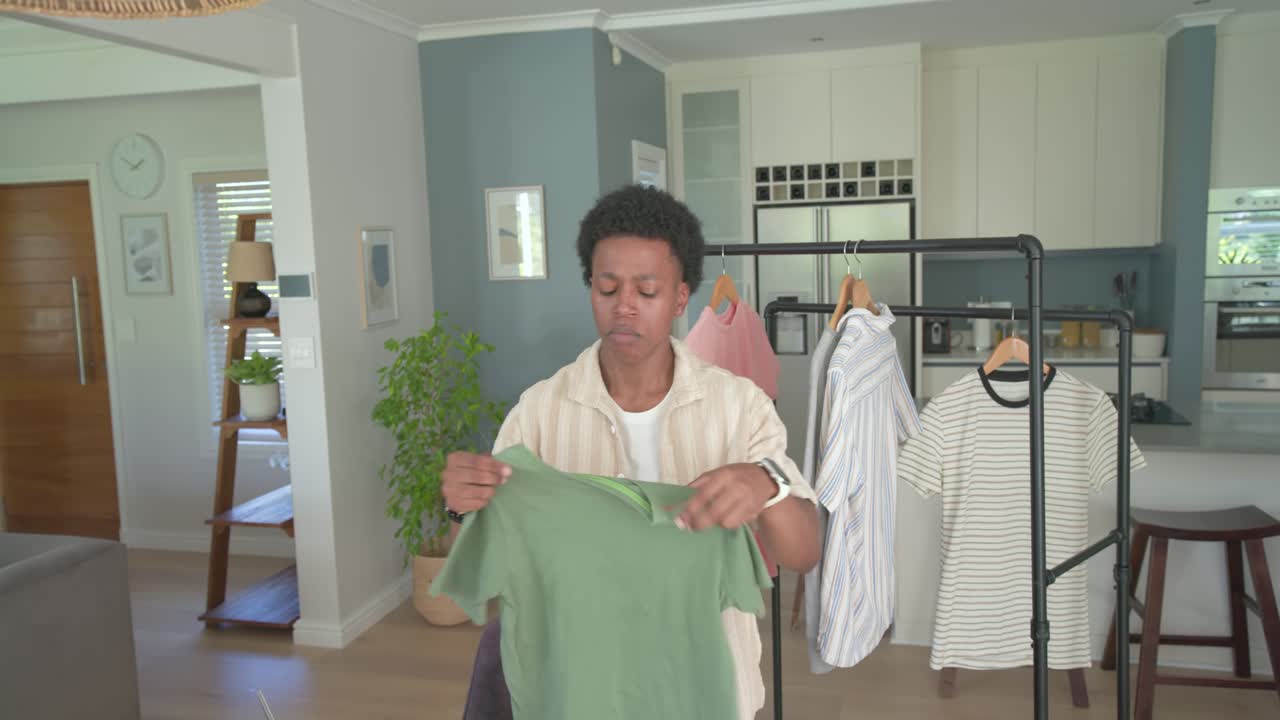 African American man choosing green Tshirt on rack, checking tag, folding, packing to ship at table