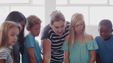 Students-With-Female-Teacher-In-Class-Collaborating-On-Project-Together