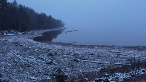 Beautiful,-lazy-snowfall-on-a-pristine-mountain-lake-during-a-nor'easter,-on-a-cold-moody,-atmospheric,-calm,-blue-evening