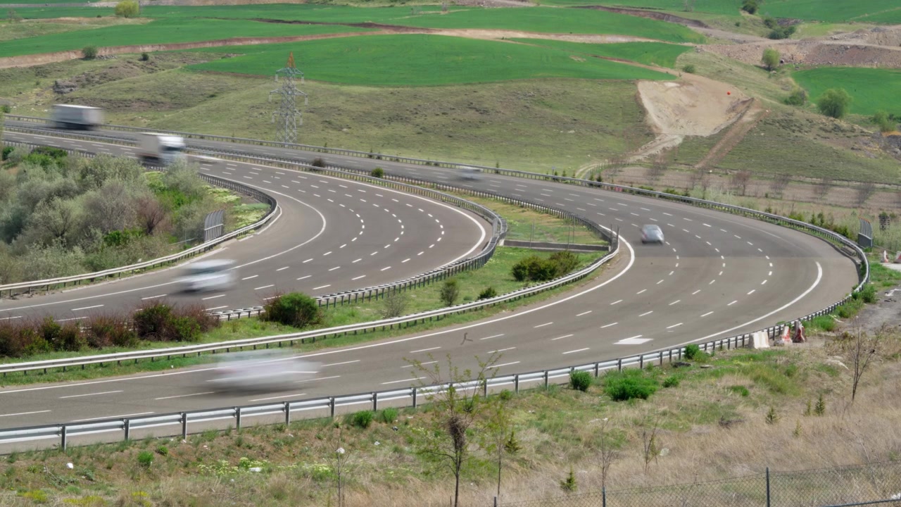 Time-lapse del traffico su un'autostrada curva attraverso un paesaggio rurale