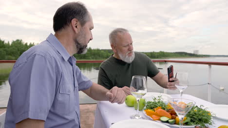 two men having dinner or lunch and taking selfies