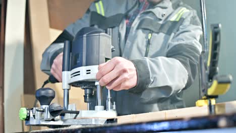 close-up of a carpenter's hand working with an manual electric cutter in a home workshop.