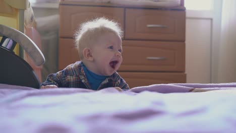 small boy plays at big bed with pink plaid in children room