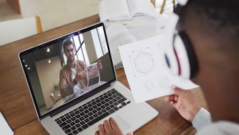 Afroamerikanischer-Männlicher-College-Student,-Der-Notizen-Hält,-Während-Er-Zu-Hause-Einen-Videoanruf-Auf-Dem-Laptop-Führt