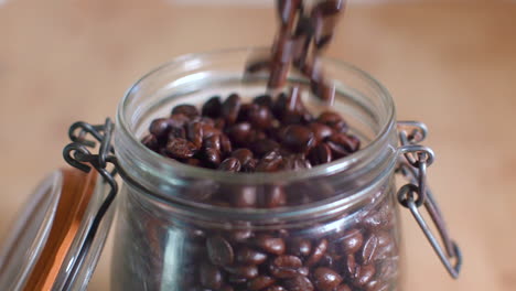 close up of pouring coffee beans into mason jar with lid in slow motion