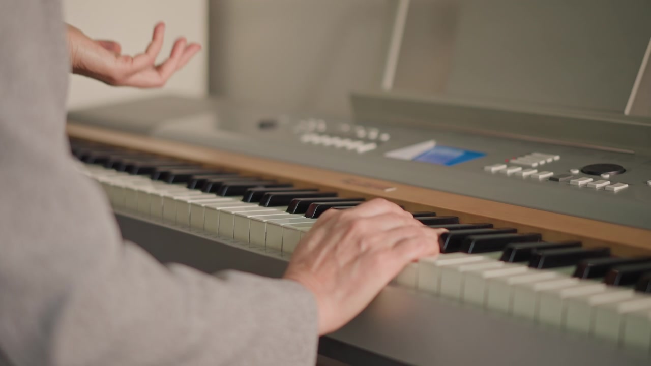 Primo piano di mani che suonano dolci melodie al pianoforte. Dita abili che accarezzano con delicatezza i tasti del pianoforte elettrico. Vista dettagliata delle mani che manovrano con maestria la tastiera con delicati movimenti delle dita.