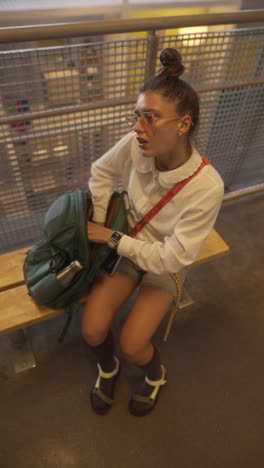teenage girl looking in a backpack on a bench