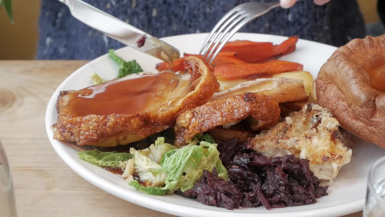 A hearty Sunday roast with crispy pork belly, vegetables, and gravy served on a plate