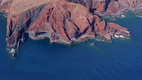 Volcanic coastal cliffs of Canary Islands, red rock formations, turquoise waters