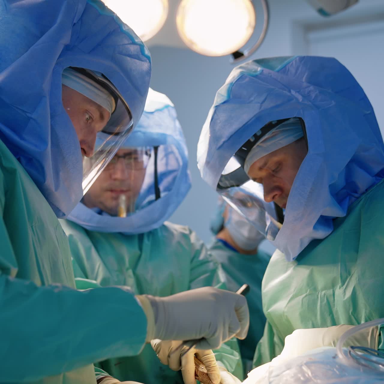 Team medico maschile che esegue un intervento ortopedico. Infermiera che passa gli strumenti ai dottori sullo sfondo