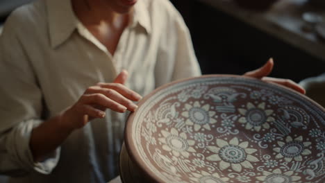 smiling ceramist touching clay plate in workshop