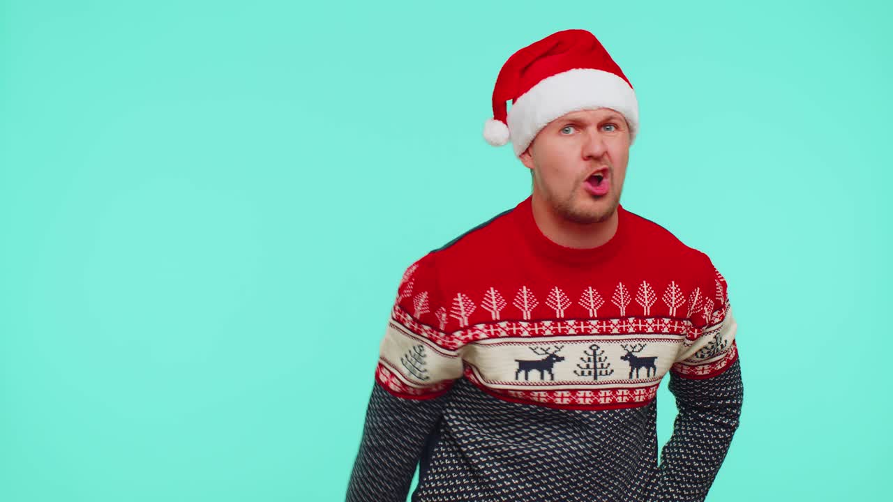 hombre disgustado con suéter de navidad gestando las manos con disgusto, culpando a los regaños por el fracaso