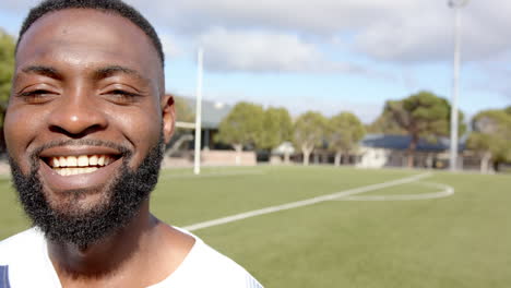 smiling african american male athlete standing on soccer field, fitness training, copy space
