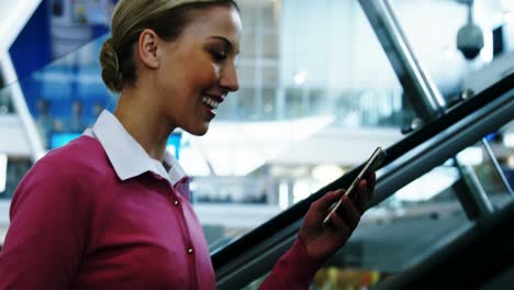 mujer en la escalera mecánica enviando mensajes de texto por teléfono móvil