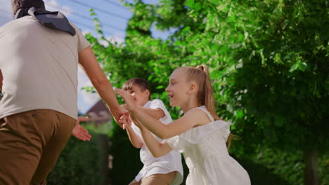 family playing blind man buff in park. kids running on backyard with parents