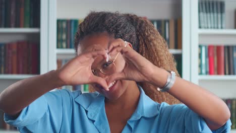 joven romántica afroamericana rizada hace forma de corazón con los dedos