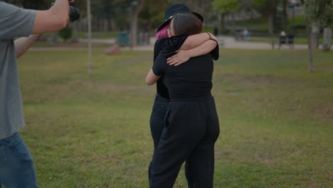 dos mujeres abrazadas en un parque.