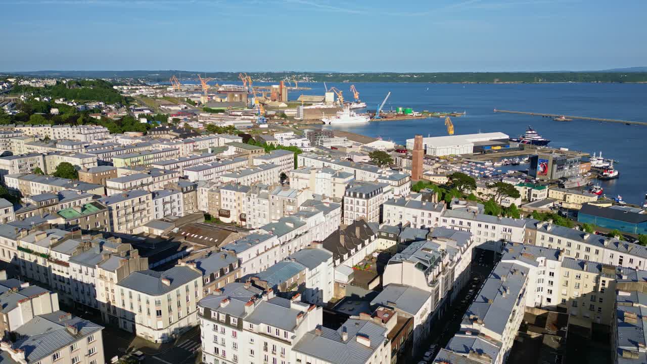 Aerial panoramic establishing of Brest port zone with industrial docks and ships along the coastline waters near apartments, early morning
